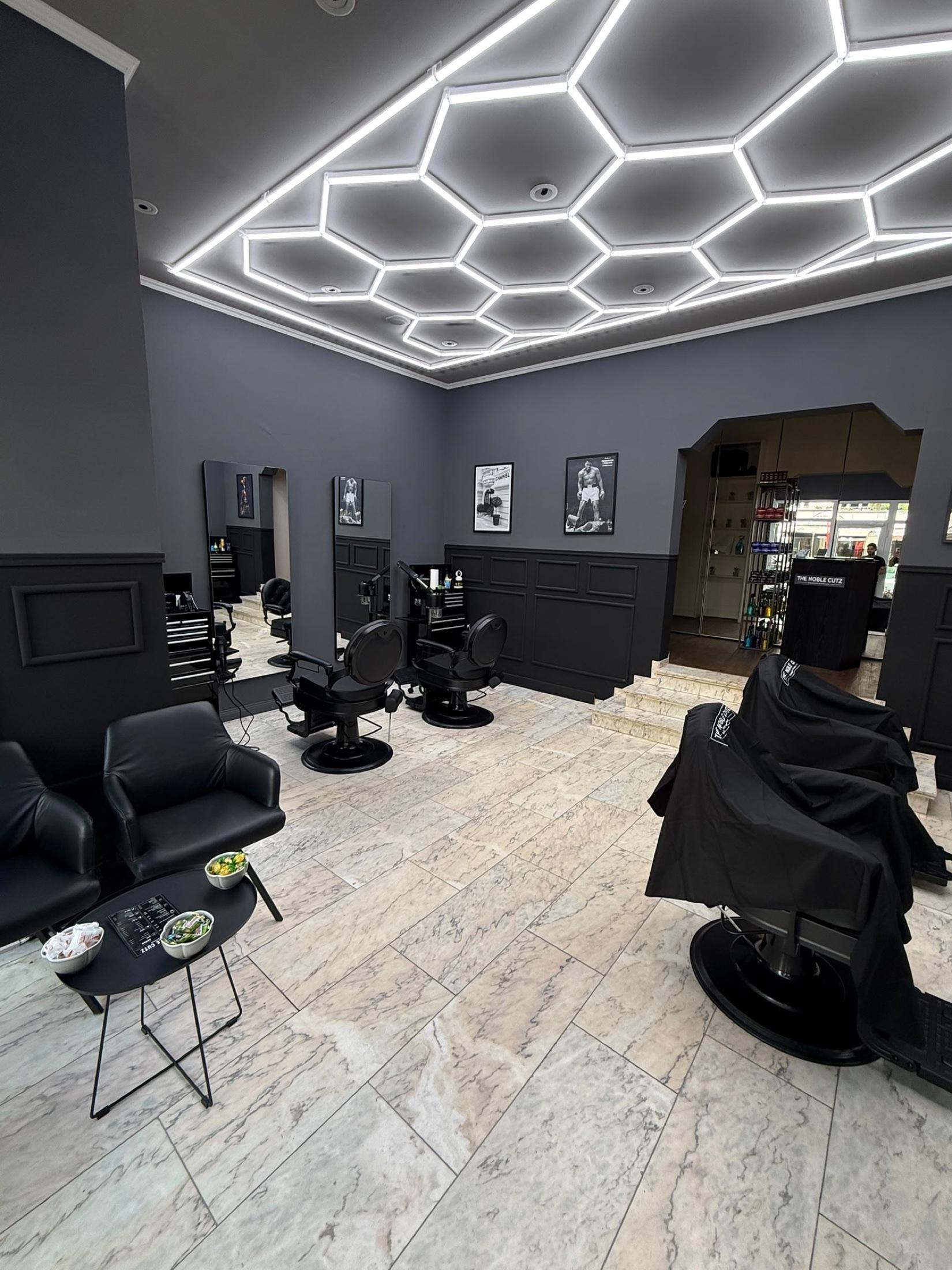 Großzügiger Innenraum des THE NOBLE CUTZ mit Lounge, Barber-Chairs und Produktdisplay